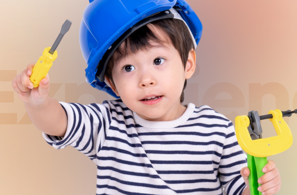 Young boy with a construction helmet and tools in his hand