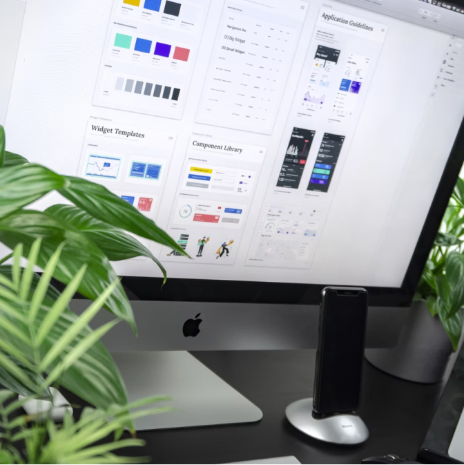 iMac on black table with a phone and plants