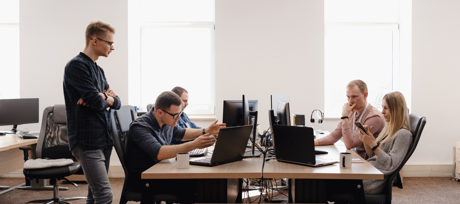 Designers working closely on a project while the team lead is discussing decisions with a team member, all of which are product design team roles