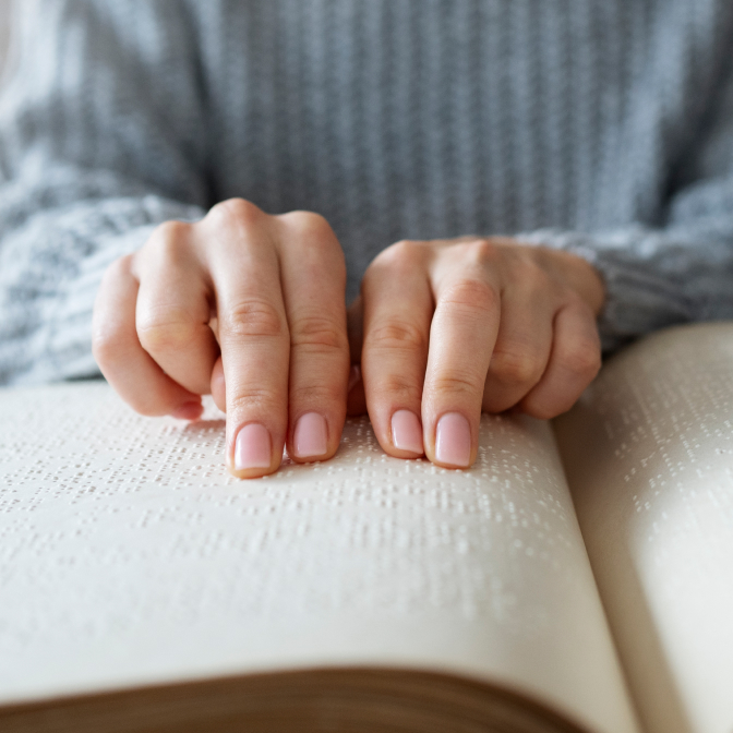 A blind woman is holding her fingers on the Braille book 