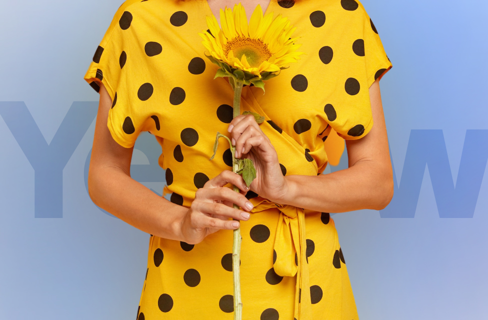 A person wearing a yellow dress with a sunflower in their hands